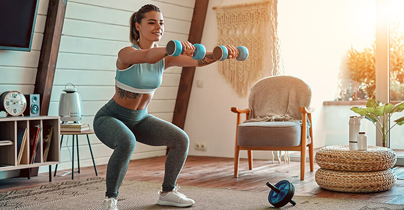 A woman in yoga pants working out in her bohemian style home.