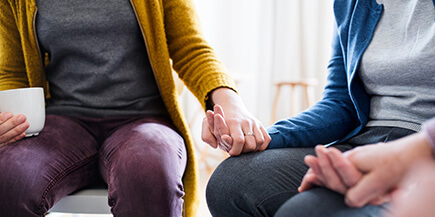 A close up shot of a group of people holding hands in a supportive manner.