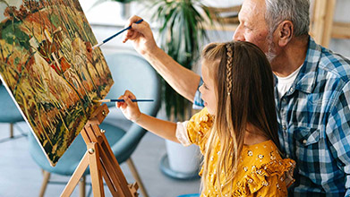 Senior man painting with his granddaughter.