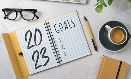 A goals planner on a table with a coffee and glasses.