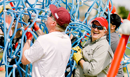 People working together on a cargo net in a playground.