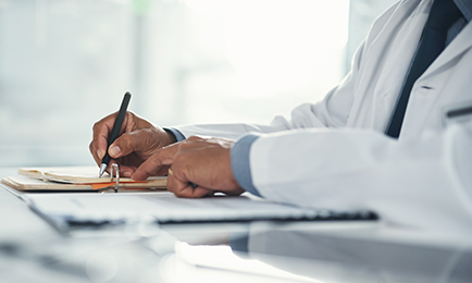 A physician sitting at a desk writing a prescription.