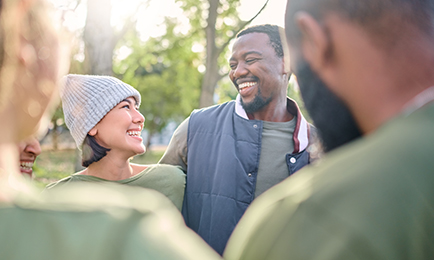 A woman and a man smiling while looking at each other surrounded by friends.