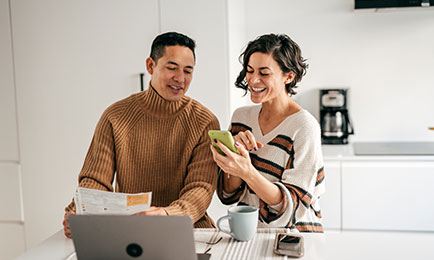 Couple smiling while going over documents and checking phone.