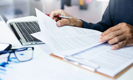 Person filling out forms and checking information.