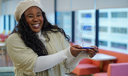 Faces of Wellness winner holding her award and smiling to the camera