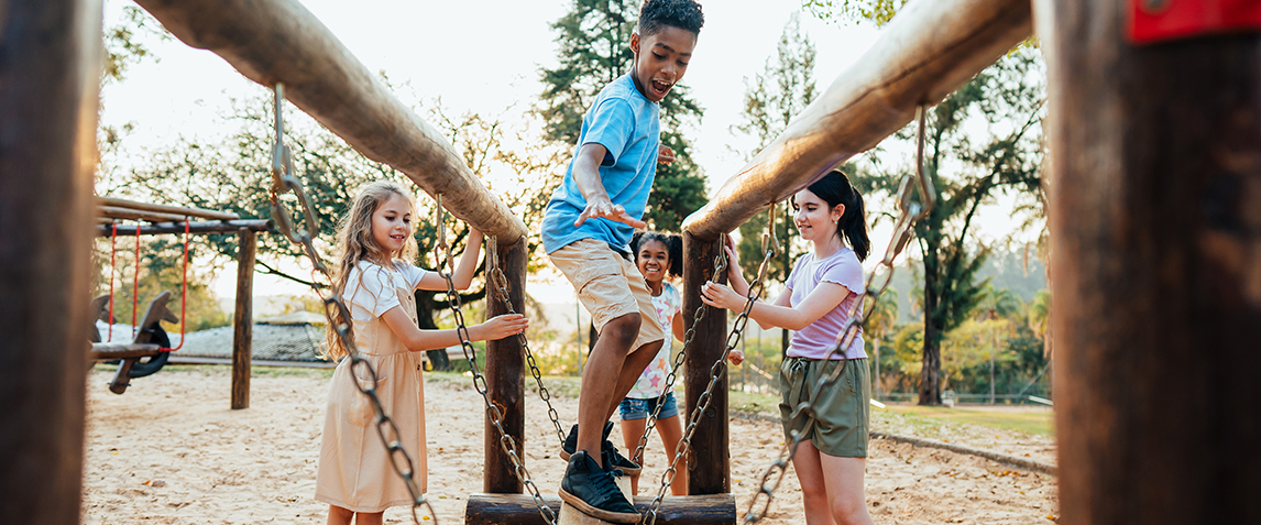 Photo of children playing in a playground. All of them are smiling and having fun.