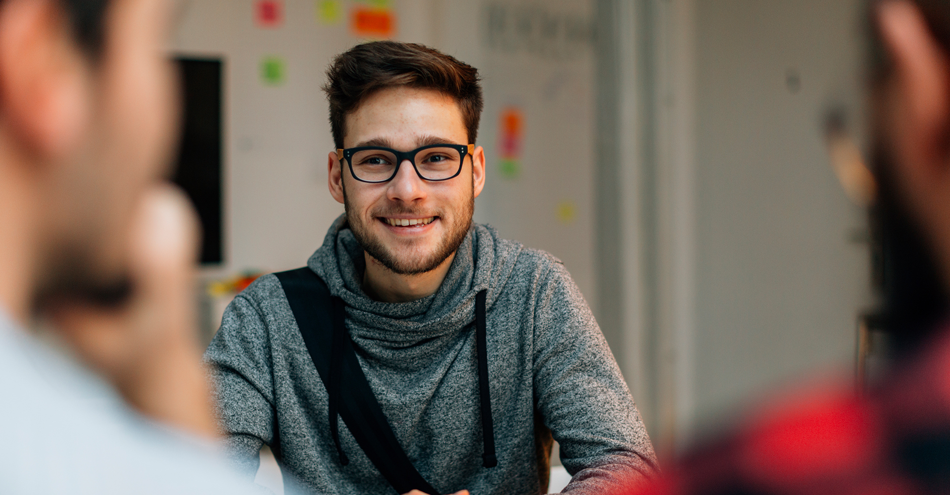 Smiling man seated at a table during a discussion.