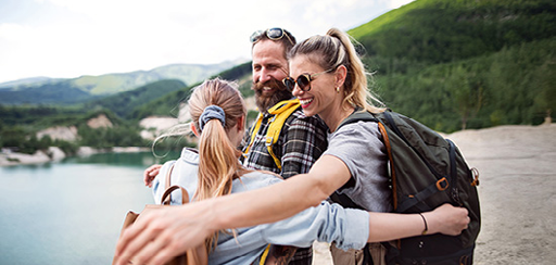 A family of 3 hugging while on vacation in the mountains.