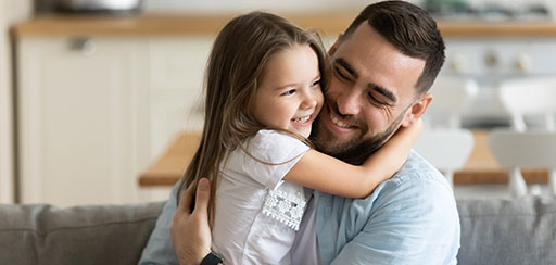 A man and a girl hugging and smiling.