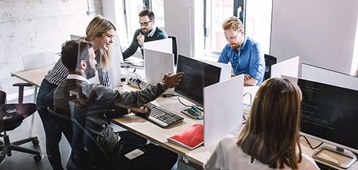 Five employees working on computers in an office.