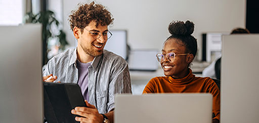 Two people smiling and consulting a tablet device.